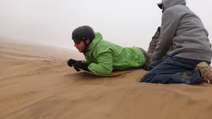 Sandboarding im Liegen in der Namib Wüste bei Swakopmund auf einfacher Holzplatte