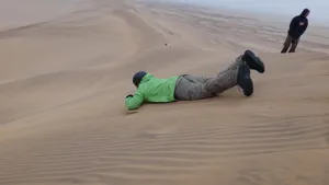 Sandboarding im Liegen in der Namib Wüste bei Swakopmund auf einfacher Holzplatte