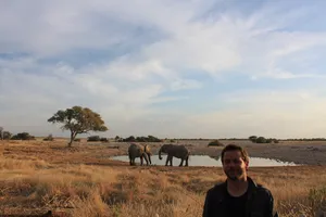 Autor vor Wasserloch mit 2 Elefanten auf Campingplatz in Namibia